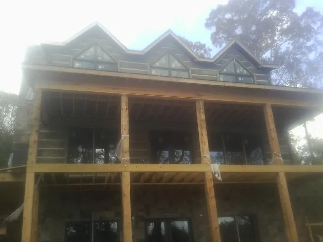 Dormers and porch framing on a large log home under construction — Roof Coating work by our crew in Saint Clair